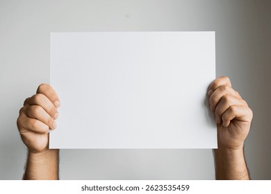 Manos que sostienen el papel blanco en blanco contra el fondo neutral