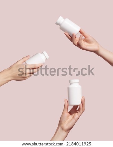 Hands holding blank white plastic tubes on pink background. Packaging for pills or capsules. Medic product branding mockup. High quality photo 