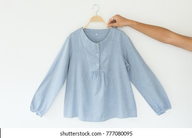 Hands Holding Blue Blouse Is Clothes Hanger On White Background.