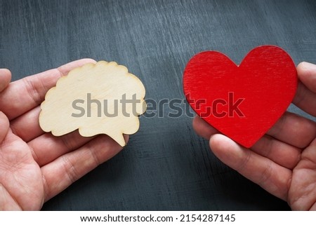 Hands holding brain and heart models. Logic or feelings.