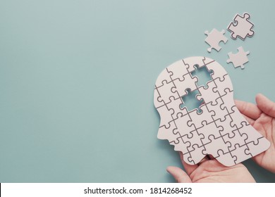 Hands holding brain with puzzle paper cutout, autism, memory loss, dementia, epilepsy and alzheimer awareness, world mental health day, world Parkinson day concept - Shutterstock ID 1814268452