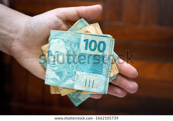 Hands holding Brazilian real notes, money from\
Brazil, notes of Real, Brazil BRL banknote, Brazilian currency,\
economy and business.
