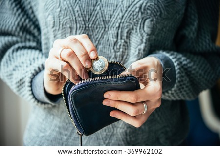 Hands holding british pound coin and small money pouch