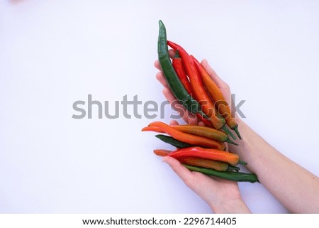 hands holding a bunch of red and green peppers