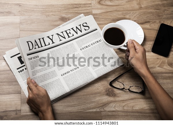 Hands Holding Business Newspaper On Wooden Stock Photo (Edit Now