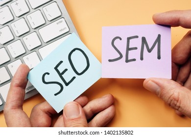 Hands Holding Cards With SEO And SEM.