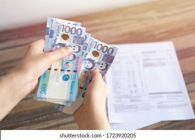 Hands holding cash banknote of one thousand Philippines peso paying bills, payment or salary.  White background, close up
