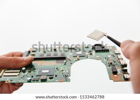 Hands holding cirquit board, laptop motherboard and tweezers with cpu microprocessor. Closeup view on white background isolated.