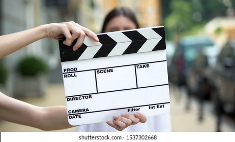 Hands Holding Clapperboard In Front Of Young Woman, Movie Scene, Production