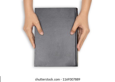 Hands holding closed book with black blank cover on white background.