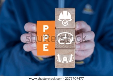 Hands holding colorful blcoks with icons and acronym: PPE. Concept of PPE Protective Personal Equipment Required Industry. Safety health and work accessories.