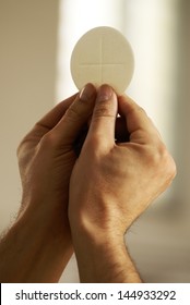 Hands holding communion wafer at church interior.