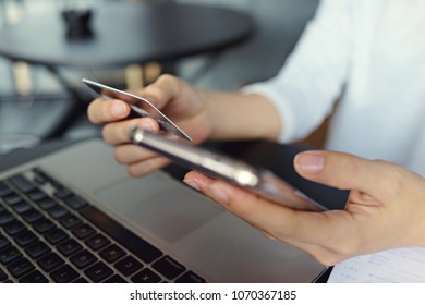 Hands holding credit card and smartphone. Using laptop and online shopping concept.