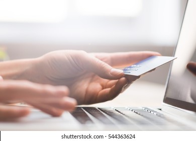 Hands holding credit card, typing on the keyboard of laptop, onine shopping detail close up