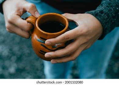 Photo of Hands holding a cup of Café de Olla, traditional from Mexico.