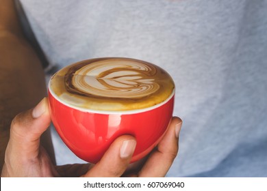 Hands Holding Cup Of Hot Coffee Latte With Heart Shaped Foam Art