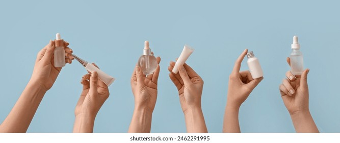 Hands holding different cosmetic products on light blue background