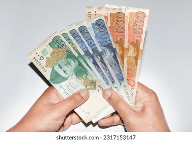 Hands holding different currency notes of Pakistani rupees on white background. 5000, 1000 and 500 currency notes.