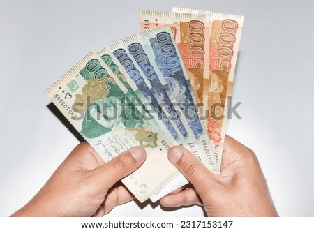 Hands holding different currency notes of Pakistani rupees on white background. 5000, 1000 and 500 currency notes.