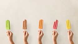 Hands Holding Different Types Of Colorful Fruit Popsicles. Strawberry, Mango, Caramel, Apple And Orange Flavor