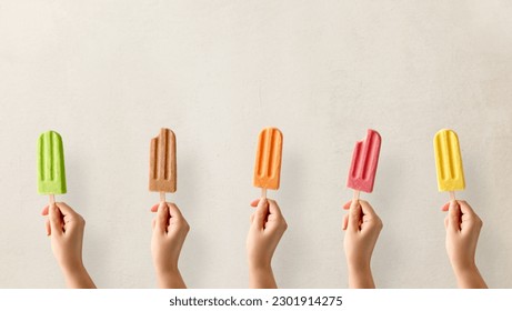 Hands holding different types of colorful fruit popsicles. Strawberry, mango, caramel, apple and orange flavor - Powered by Shutterstock