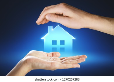 Hands Holding Digital House Icon On Blue Background. Real Estate And Smart Home Concept