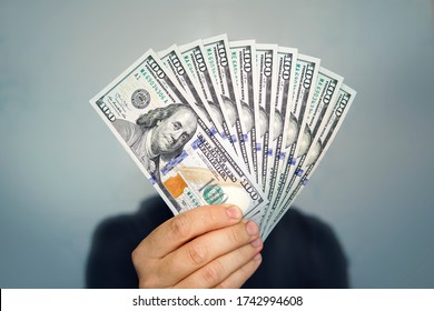 Hands holding dollar cash. 1000 dollars in 100 bills in a man's hand close-up on a dark background. - Shutterstock ID 1742994608