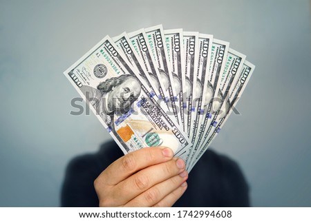 Hands holding dollar cash. 1000 dollars in 100 bills in a man's hand close-up on a dark background.