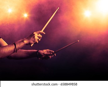 Hands holding drum sticks, backlit