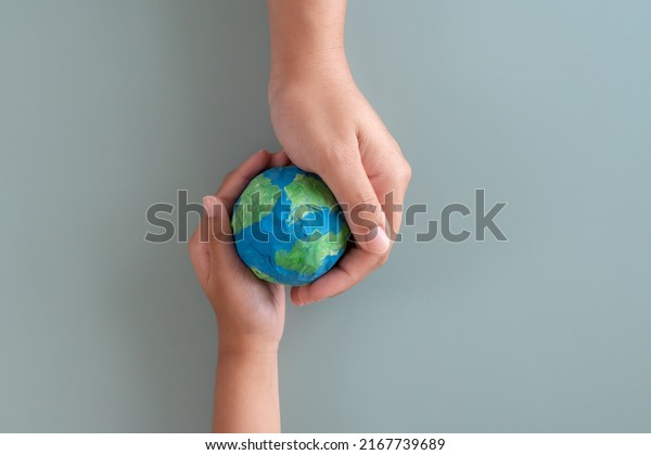 Hands holding earth paper and water paint. Concept\
of protecting the world from global warming. Sustainability topic\
to save the world.