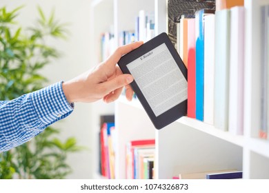 Hands holding ebook on bookshelf background.Copy space on digital tablet display