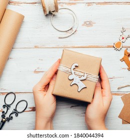 Hands Are Holding Gift, Wrapped In Recycled Brown Paper With Handmade Toppers , Christmas Background With Minimalist Style Wrapping, Top View Flat Lay