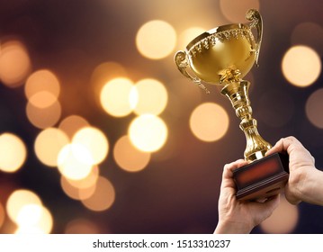 Hands holding golden trophy on a light background - Shutterstock ID 1513310237