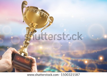 Hands holding golden trophy on blue sky background