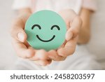 Hands holding green happy smile face paper cut, good feedback rating,think positive, child wellness,world mental health day, Compliment Day
