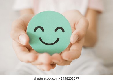 Hands holding green happy smile face paper cut, good feedback rating,think positive, child wellness,world mental health day, Compliment Day
 - Powered by Shutterstock