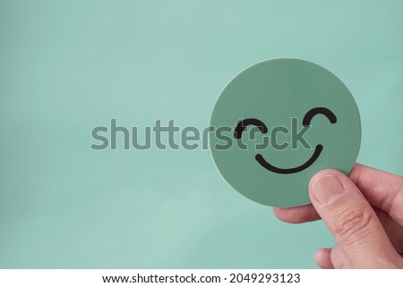 Hands holding green happy smile face paper cut, good feedback rating,positive customer review, experience, satisfaction survey ,mental health assessment, child wellness,world mental health day concept