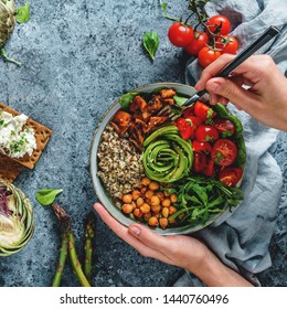 Hands Holding Healthy Superbowl Or Buddha Bowl With Salad, Sweet Potatoes, Chickpeas, Quinoa, Tomatoes, Arugula, Avocado On Light Blue Background. Healthy Vegan Food, Clean Eating, Top View