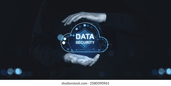 Hands holding a holographic cloud with Data Security text and shield graphic, glowing blue connections, on a dark background. Concept of cybersecurity - Powered by Shutterstock - Get 15% off with code: PIKWIZARD15