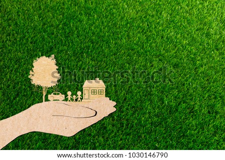 hands holding home family car and tree of grass background paper cut