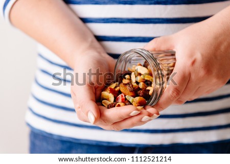 Hands holding a jar of nuts and dried fruits. Healthy breakfast. Sweet and healthy food, snack
