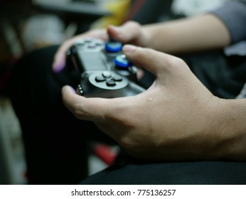 hands holding a joystick controller while playing a video games.