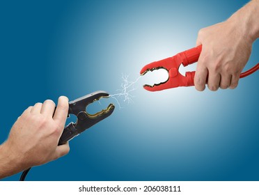 Hands Holding Jump Start Connectors With Sparks Between