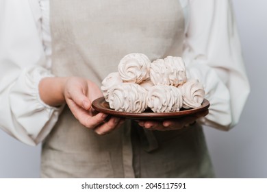 hands are holding a large plate with sweet marshmallows. Home-made confectionery. Pink sweets