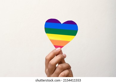 Hands Holding LGBT Heart, Lgbt Pride. Rainbow Gay Flag Heart. Symbol. A Paper Cutout Heart Colored Like A LGBT Flag Isolated On White Background