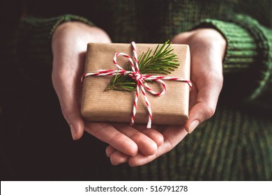 Hands holding little gift with red bow. Close up.