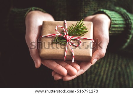 Hands holding little gift with red bow. Close up.