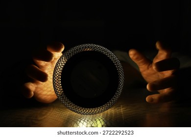 Hands Holding Mesh Sphere in Dramatic Low Light with Artistic Shadows