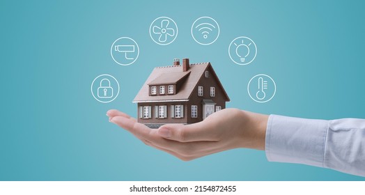 Hands Holding A Miniature Home Model With Icons, Smart Home Automation Concept