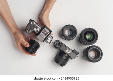 Hands holding modern mirrorless camera with lenses on white background. Photographer's equipment